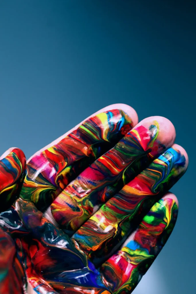 Close-up of hand covered in colourful paint representing creativity, art and self-expression