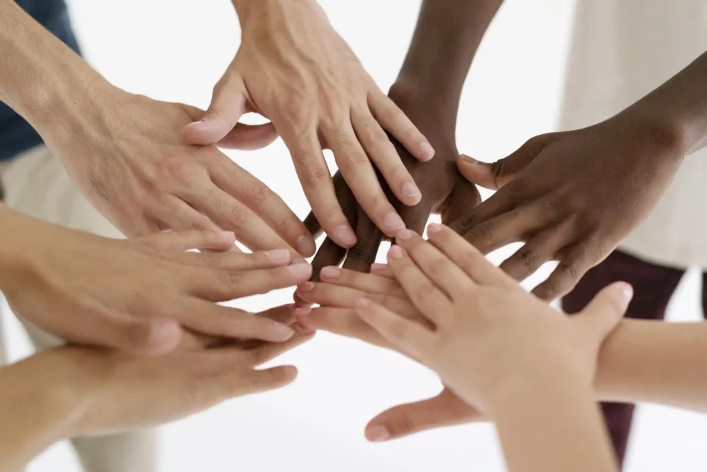 Diverse group of hands stacked together representing teamwork, unity and community support
