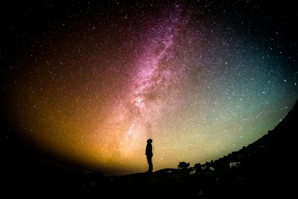 Silhouette of person standing under Milky Way galaxy with vibrant night sky and stars