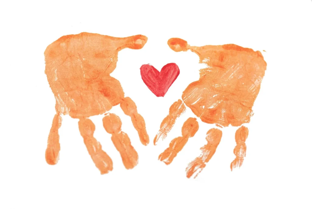 Painted handprints with red heart in centre symbolising love, family and connection